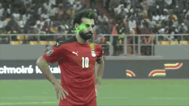 a soccer player with the number 10 on his jersey stands on the field