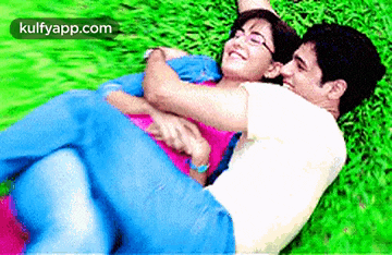 a man is carrying a woman in his arms in the grass .