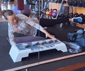 a woman is doing exercises in a gym while looking at herself in the mirror ..