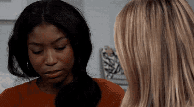 two women are looking at each other with one wearing a red sweater