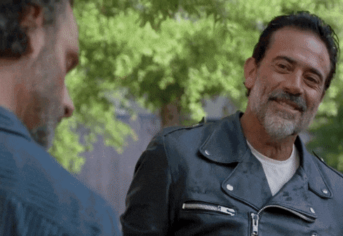 a man with a beard and a leather jacket is smiling at another man .