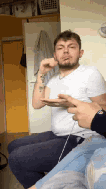 a man with a tattoo on his arm is sitting next to another man