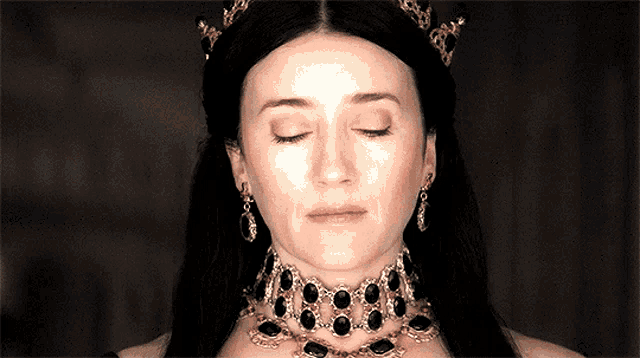 a woman with her eyes closed wearing a tiara and a choker
