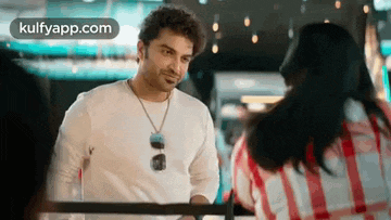 a man in a white shirt is talking to a woman in a red and white plaid shirt .