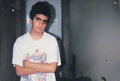 a young boy wearing a t-shirt that says ' avengers ' on it stands with his arms crossed