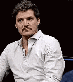 a man with a mustache and a white shirt is sitting in a chair .