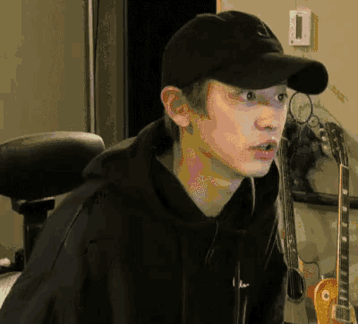 a man wearing a black hat and a black hoodie looks surprised