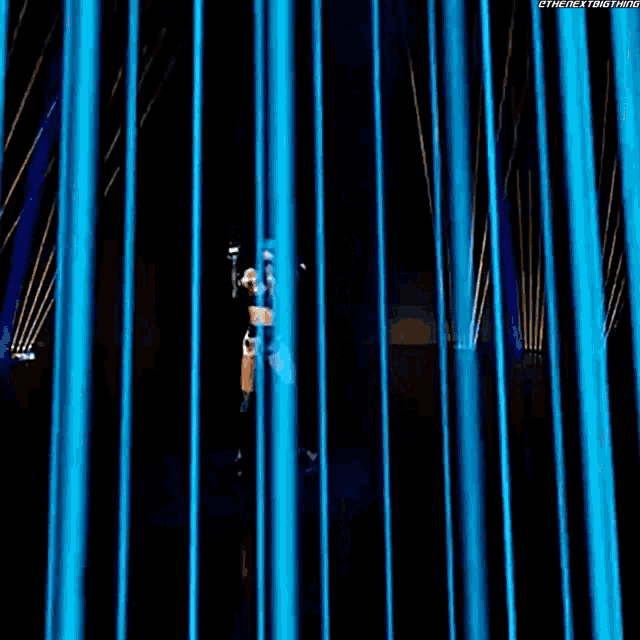 a person is standing in a dark room with blue lights behind them and the words " the next thing " on the bottom right