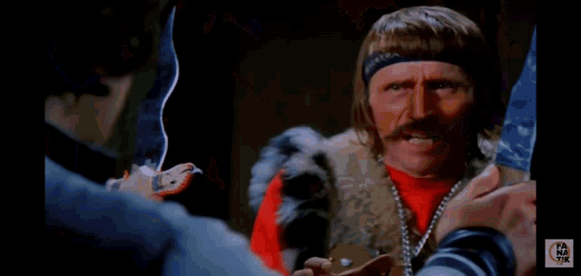 a man with a mustache is wearing a red shirt and a necklace .