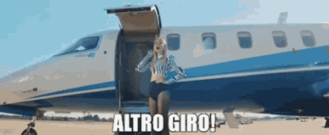 a woman is standing in front of a plane with the words altro giro written below her