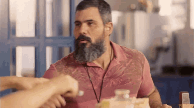 a man with a beard is wearing a pink shirt and a lanyard around his neck
