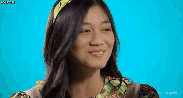 a woman wearing a colorful headband is smiling with her eyes closed .