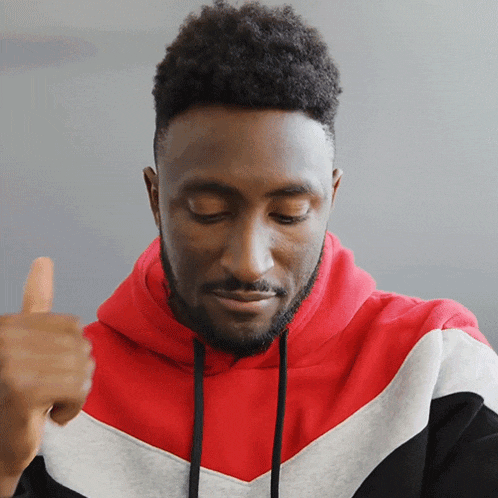 a man wearing a red black and white striped hoodie giving a thumbs up