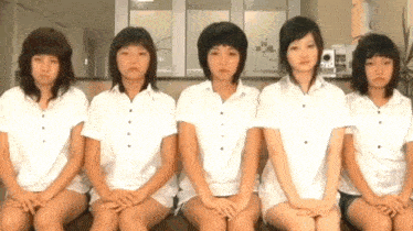 a group of girls are sitting in a row with their hands folded