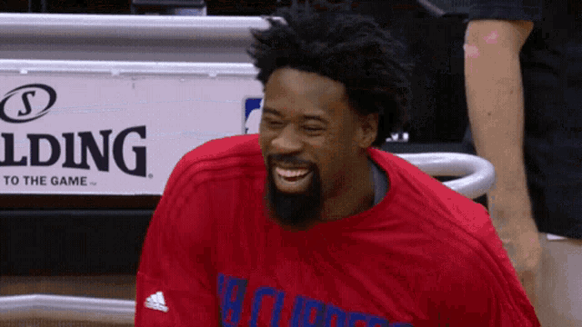 a man wearing a red shirt with the word clippers on it smiles