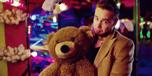 a man in a suit is holding a teddy bear in his arms .