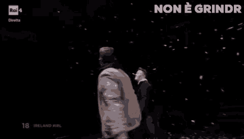 two men are holding hands on a stage in the dark .