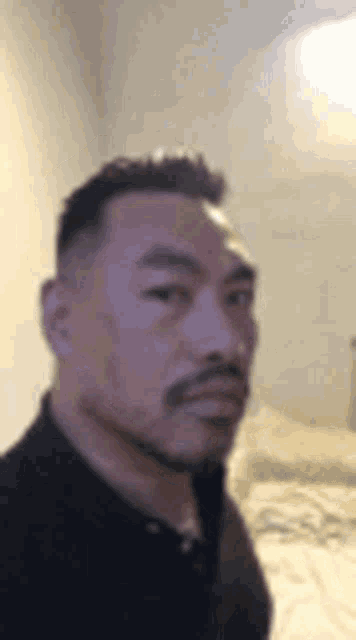 a man with a beard is taking a picture of himself in a bedroom .