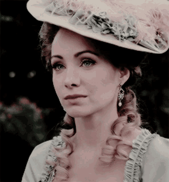 a woman is wearing a hat with feathers on it