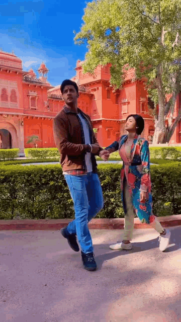 a man and a woman are walking in front of a building