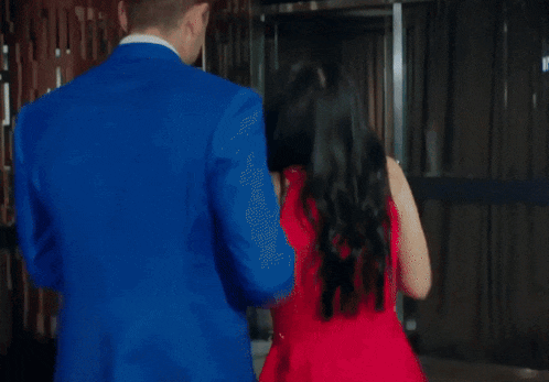 a man in a blue suit and a woman in a red dress are walking