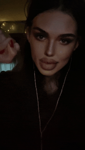 a woman with red nails is sticking her tongue out while wearing headphones