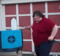 a man in a red shirt is standing in front of a blue box with a target on it ..