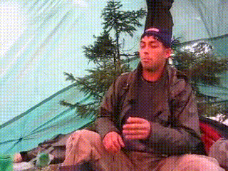 a man sitting in a tent with his eyes closed and a beanie on