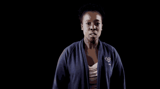 a woman is wearing a purple jacket with a white logo on it