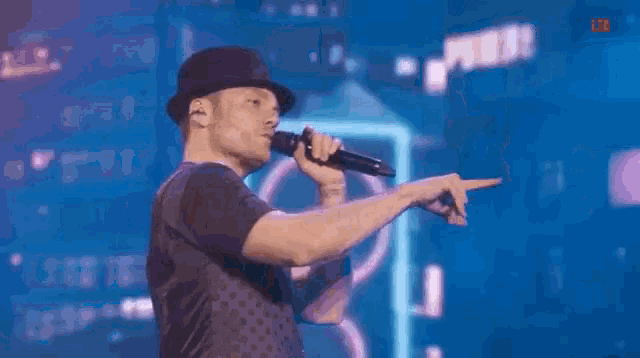 a man wearing a hat is singing into a microphone .