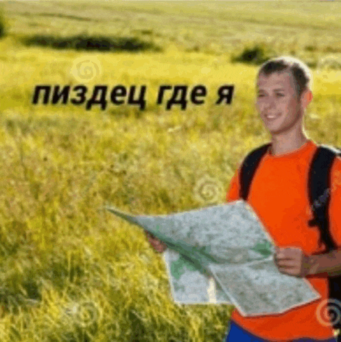 a man is standing in a field holding a map and smiling .