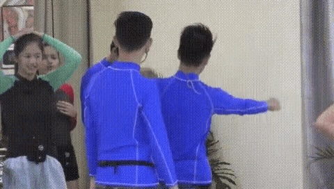 a group of people are standing next to each other in a room wearing blue shirts .