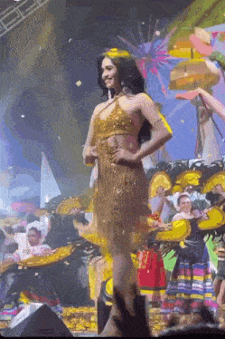 a woman in a gold dress stands on a stage