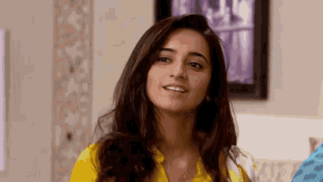 a woman in a yellow shirt is looking at the camera .