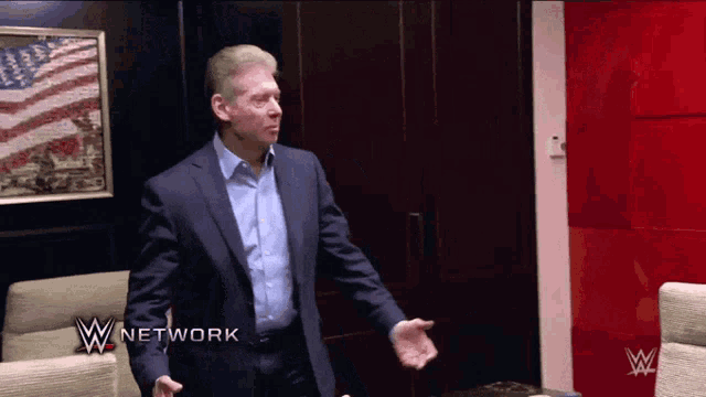 a man in a suit is standing in front of a red wall with w network written on it