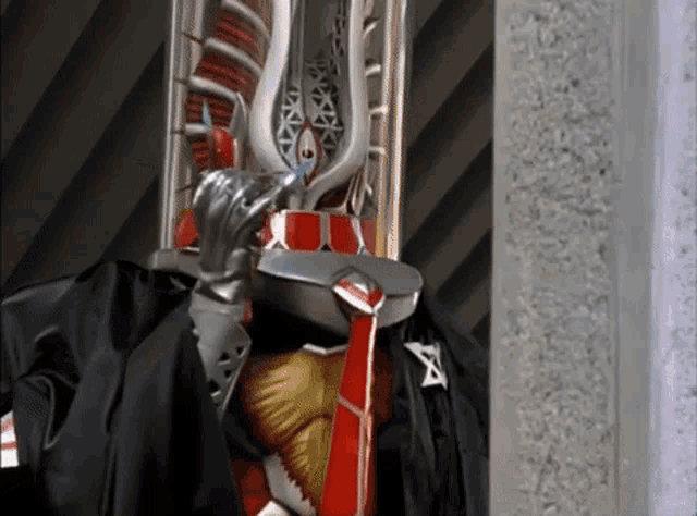 a man in a costume with a sword on his head is standing next to a wall