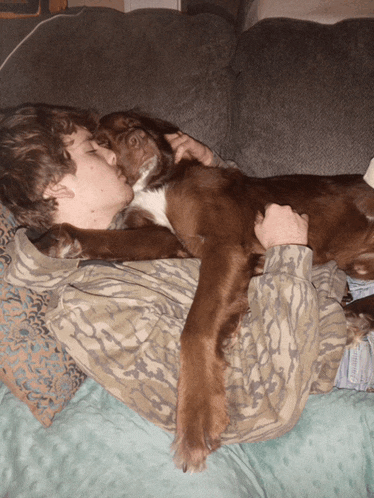 a man is laying on a couch with a brown dog