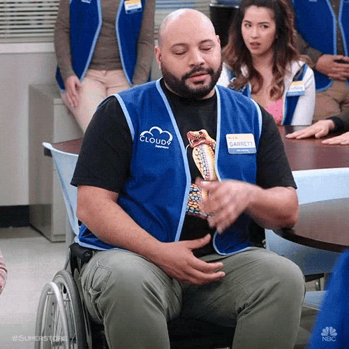 a man in a wheelchair wearing a blue vest that says cloudy on it