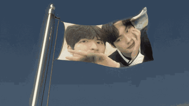 a flag with a picture of two men on it against a blue sky