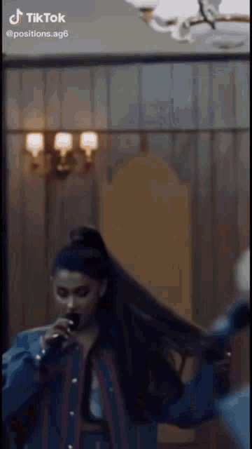 ariana grande is singing into a microphone in a room .