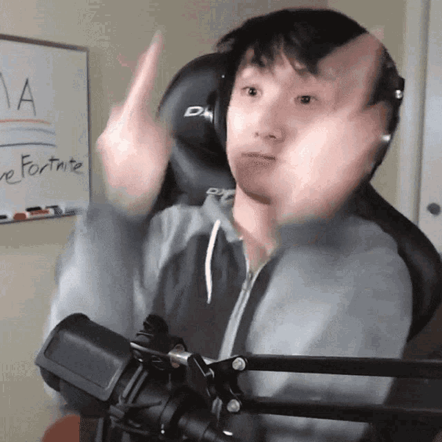 a man wearing headphones is giving the middle finger in front of a whiteboard that says fortnite