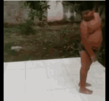 a young boy is standing on a tiled floor in a yard .