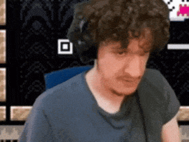 a man with curly hair wearing headphones is sitting in front of a pixelated background .