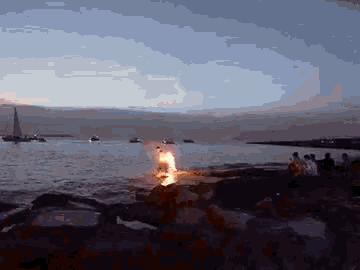 a fire is burning on the shore of a lake