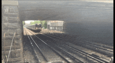 a train is going under a bridge with the letter n on the side of it
