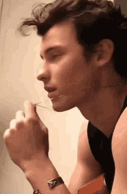a close up of a man holding a pair of scissors to his mouth .