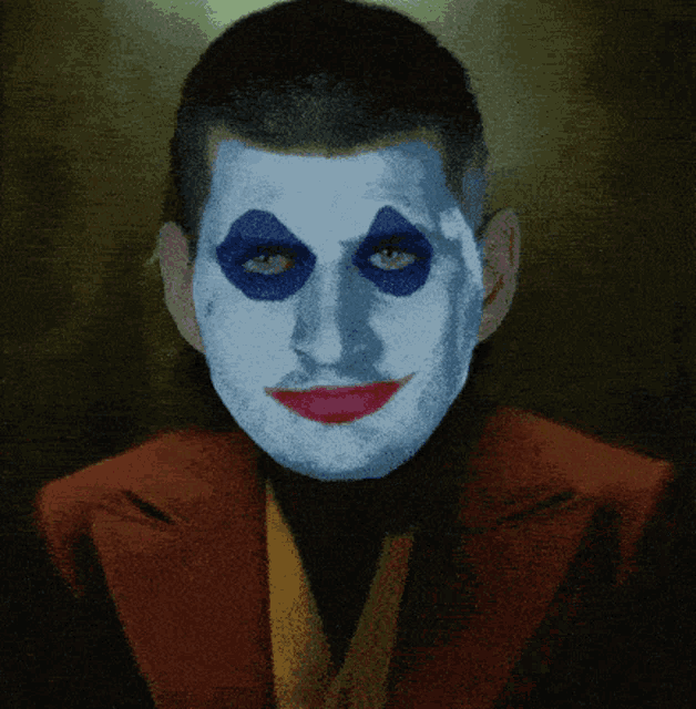a man with blue eyes and red lips is wearing a red jacket