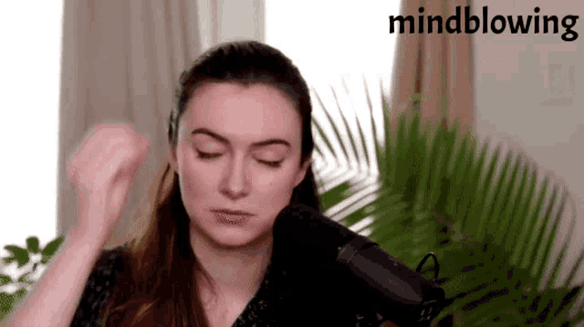 a woman is singing into a microphone with the words mindblowing behind her