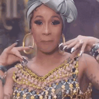 a woman wearing a turban , earrings and a dress is making a funny face .