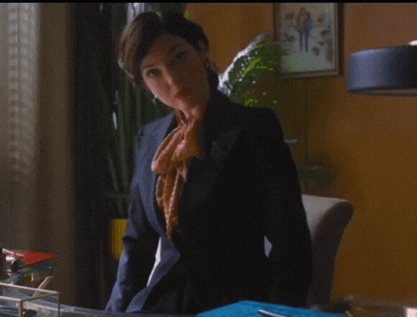 a woman in a suit is standing in front of a desk